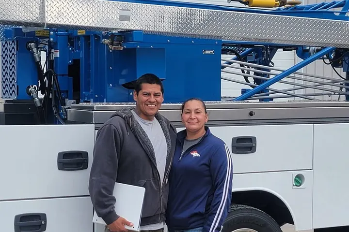 Two members of the 307 Water Well Service team standing in front of their white service truck and blue pump hoist.